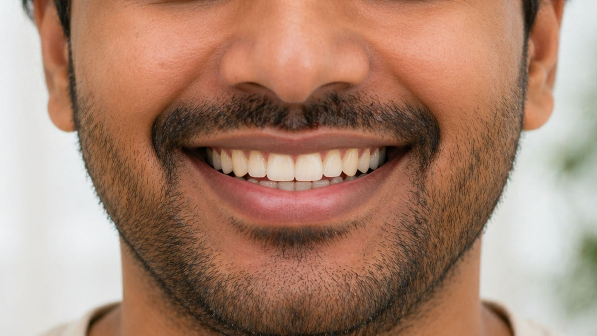 Close-up of an Indian man smiling, showing natural teeth, representing hypochlorous acid oral care and fresh breath