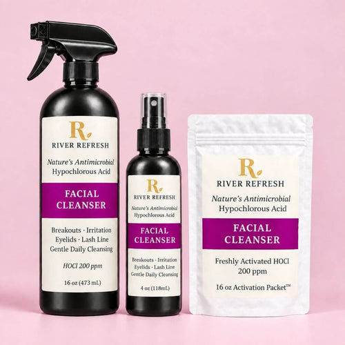 River Refresh Hypochlorous Acid Spray Facial Cleanser Starter Kit set including a 16 oz spray bottle, a 4 oz spray bottle, and a 16 oz activation packet, all in black packaging with white and purple labels, set against a solid pink background.