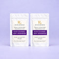 Two white River Refresh hand cleanser and body deodorizer activation packets for 32 oz refill standing upright side by side on a light lavender background.
