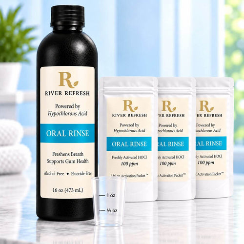 River Refresh Oral Rinse set including a 16 oz black bottle, three activation packets, and a small measuring cup on a light reflective surface.